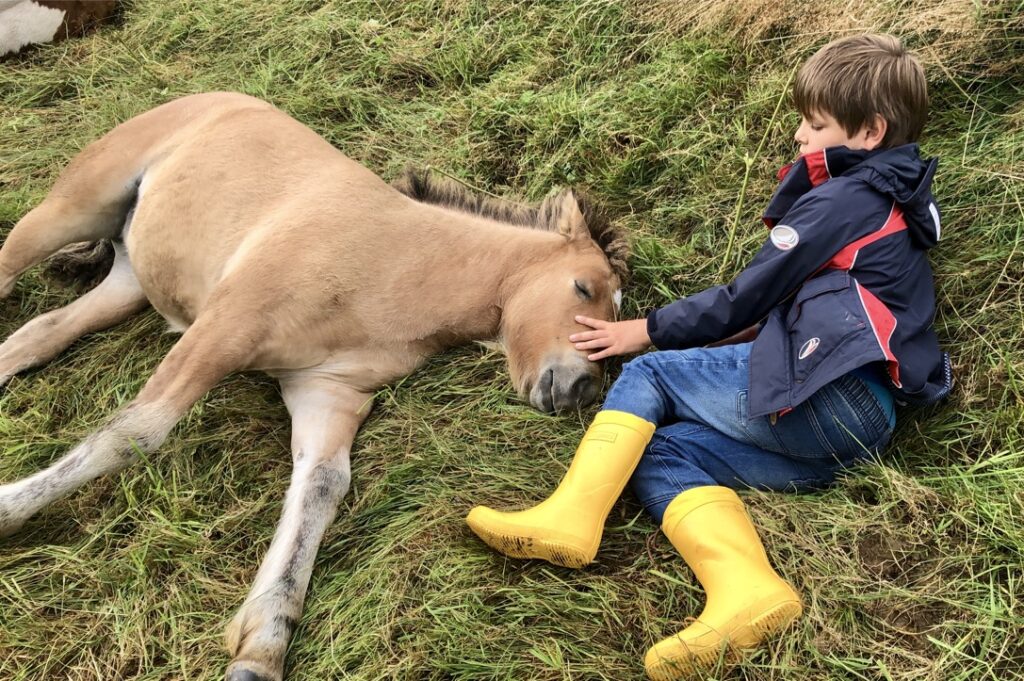 Anouk liegt im Gras mit einem Kind